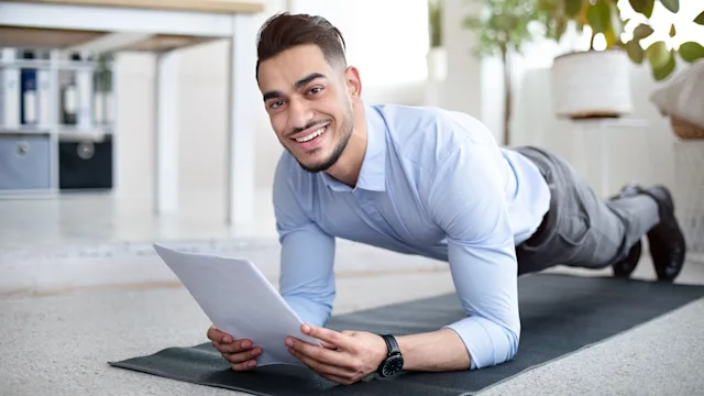Employer-sponsored: man doing plank exercise at work 1342030102