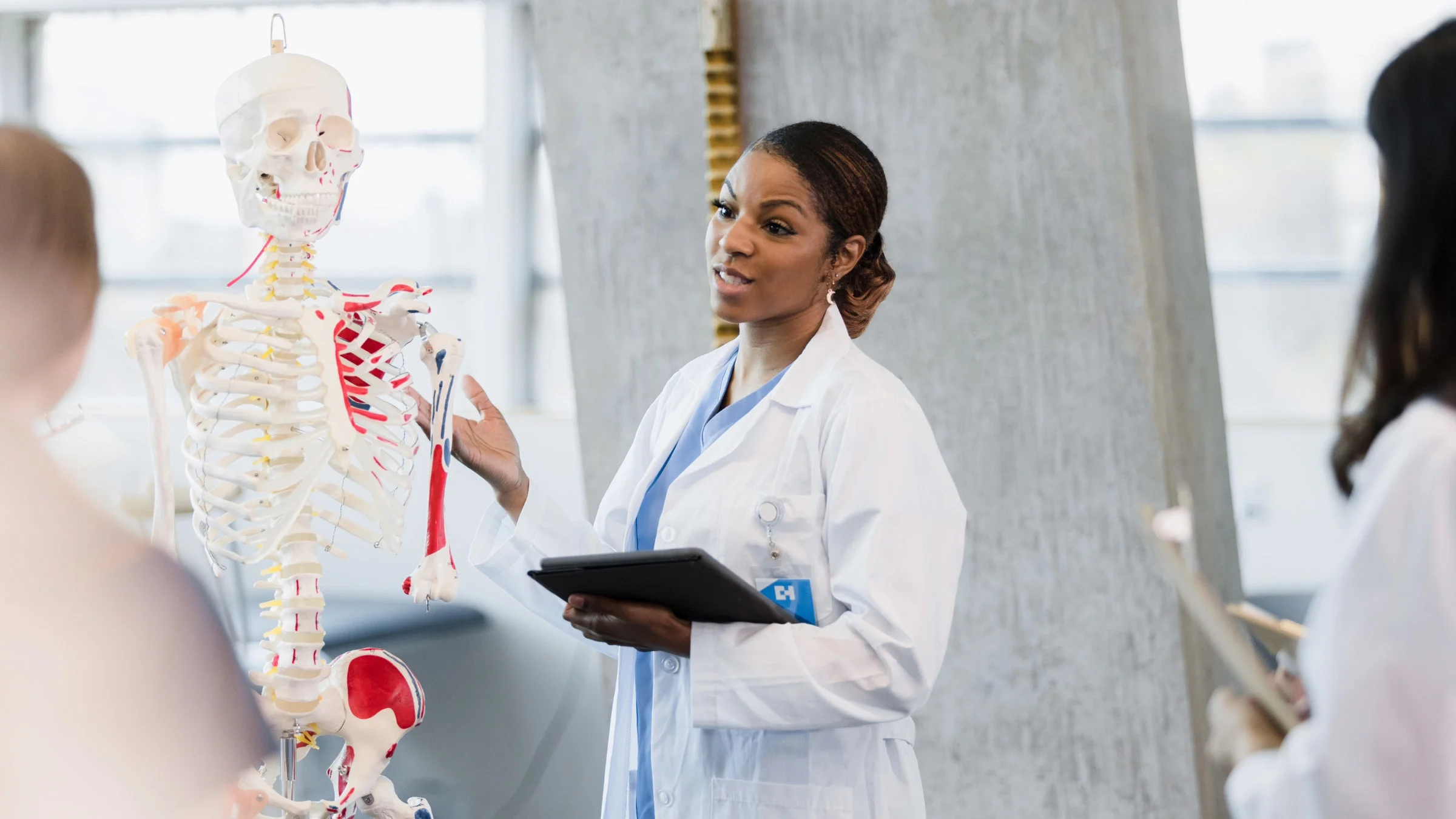A medical school professor explaining anatomy using a skeleton.