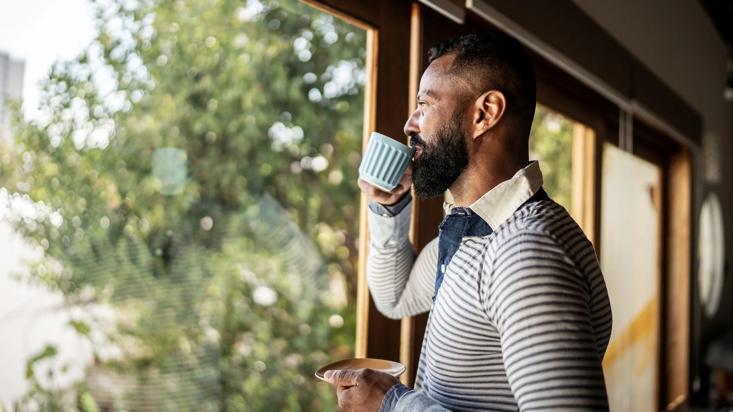 A man is drinking tea and contemplating at home.