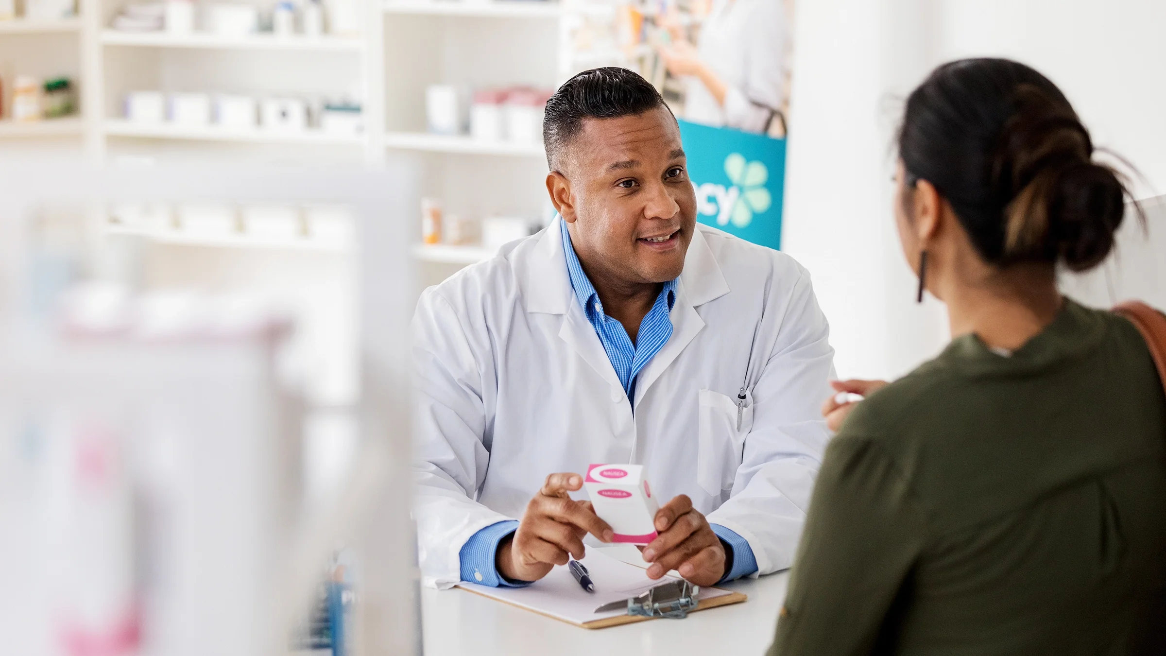 A pharmacist discusses medicine with a customer.