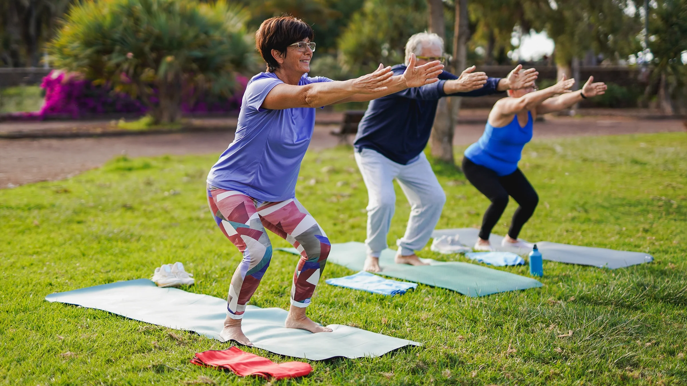 A group of older people are doing yoga exercises at a city park.