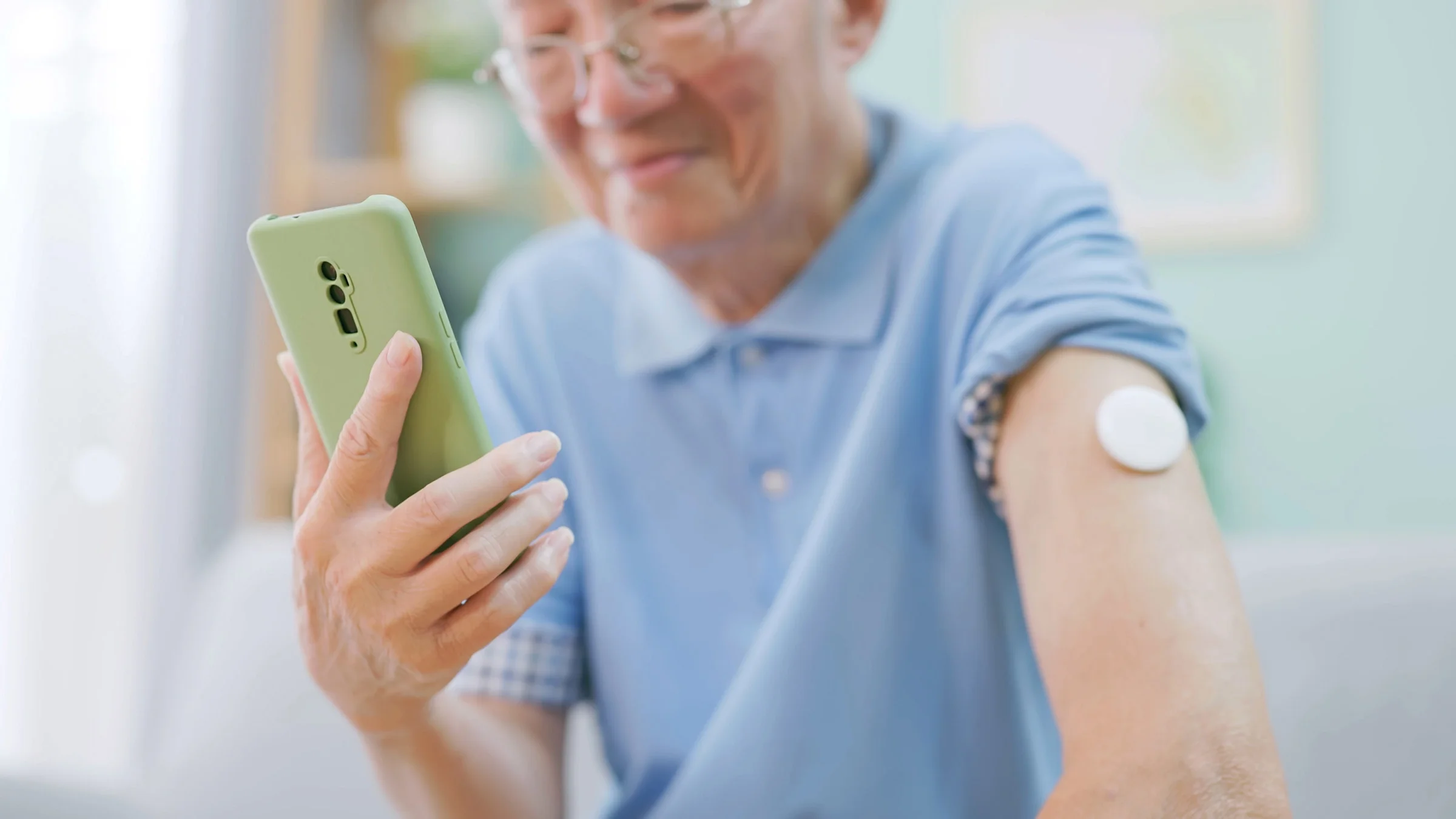 A man with a glucose monitor looking something up on his phone.