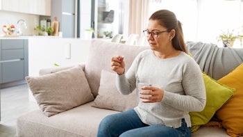 chantix: woman taking medicine with glass of water 1461688533