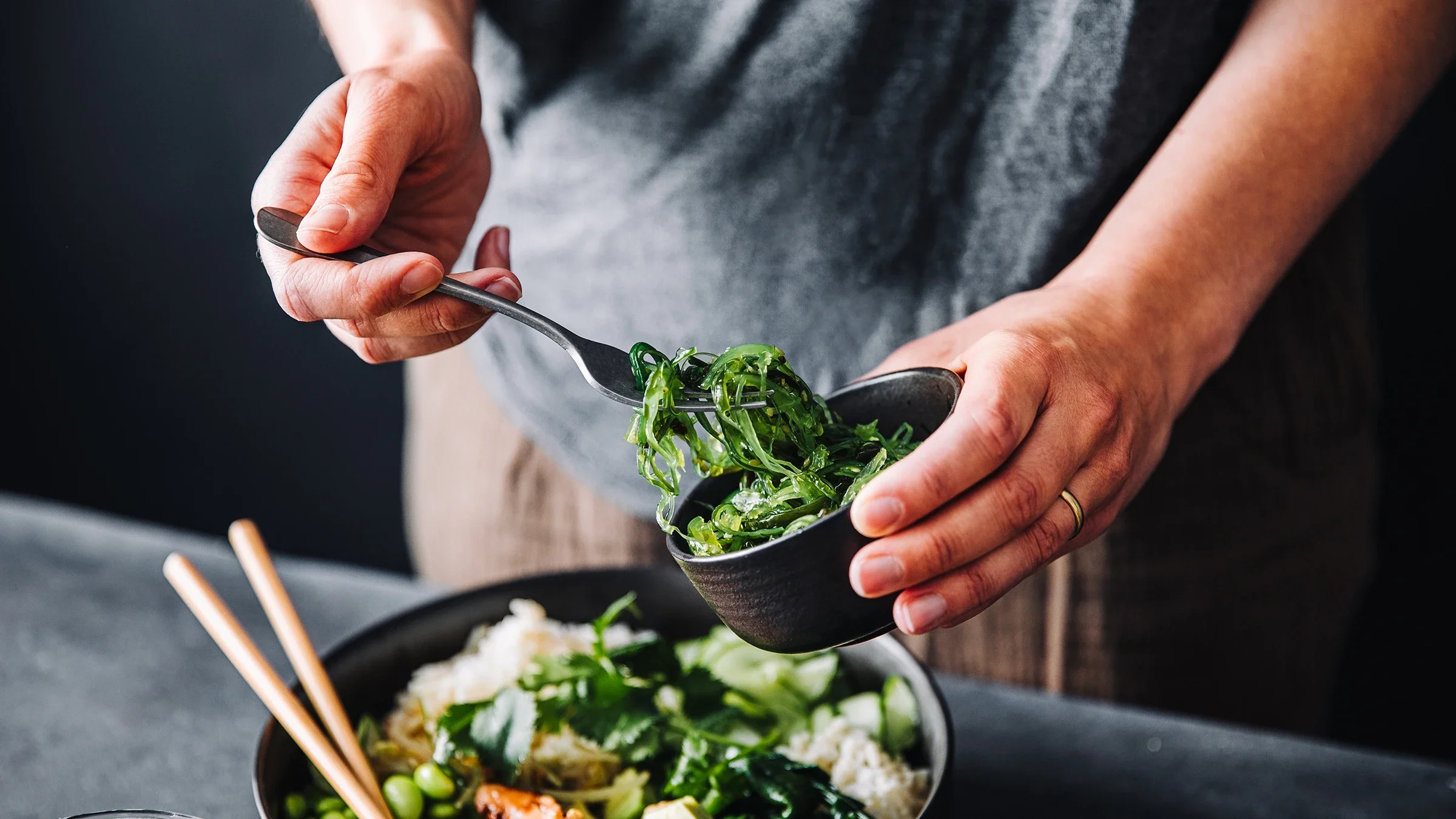 A person adds some seaweed to their vegetable bowl. Fiber can help with constipation, but eating too much of it can cause some unwanted side effects.