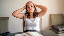 A woman sits at a table looking stressed.
José Araújo/E+ via Getty Images