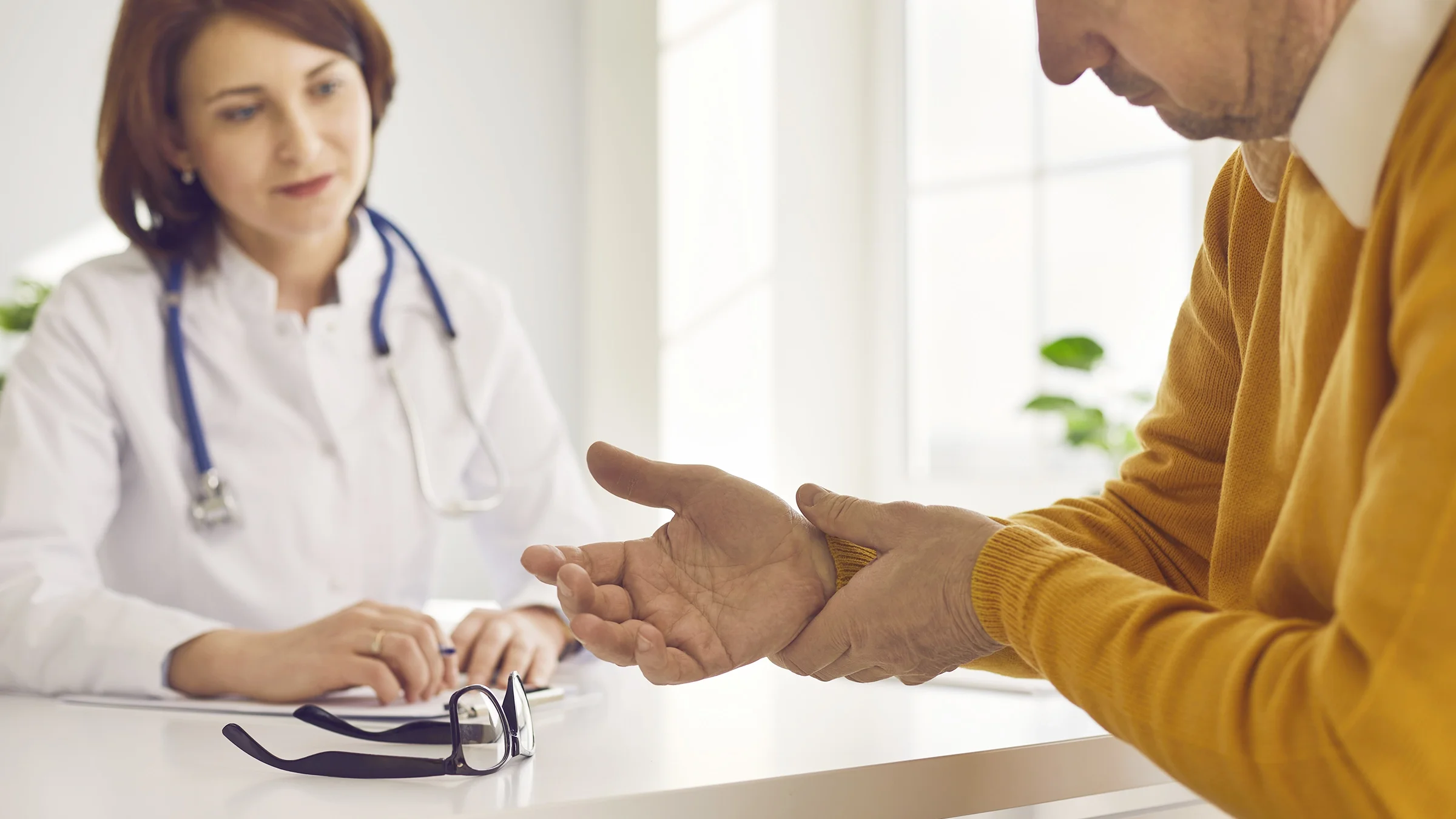 An older adult grasps their wrist as their provider watches.