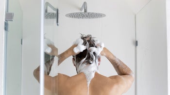 Plaque psoriasis: man applying shampoo to scalp in shower 1305364247