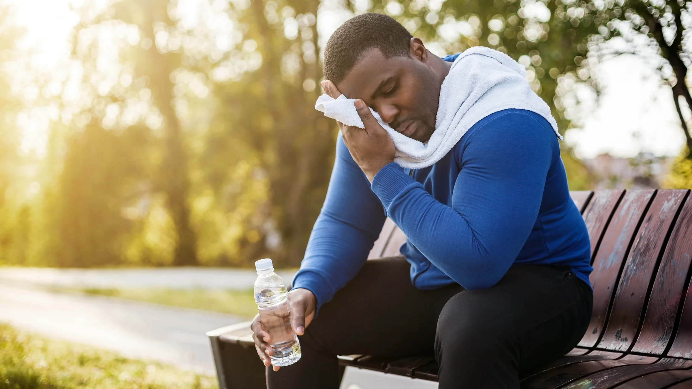 A man wipes sweat with a towel after exercising. 