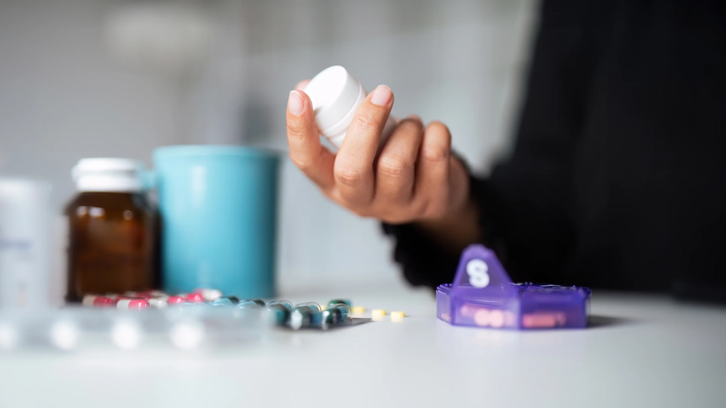 A hand is holding a white prescription bottle in a close-up.