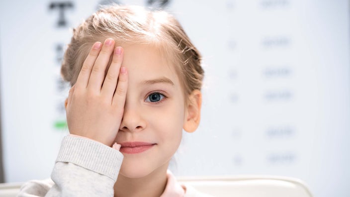 Portrait of a little girl with her hand covering one eye for an eye test.