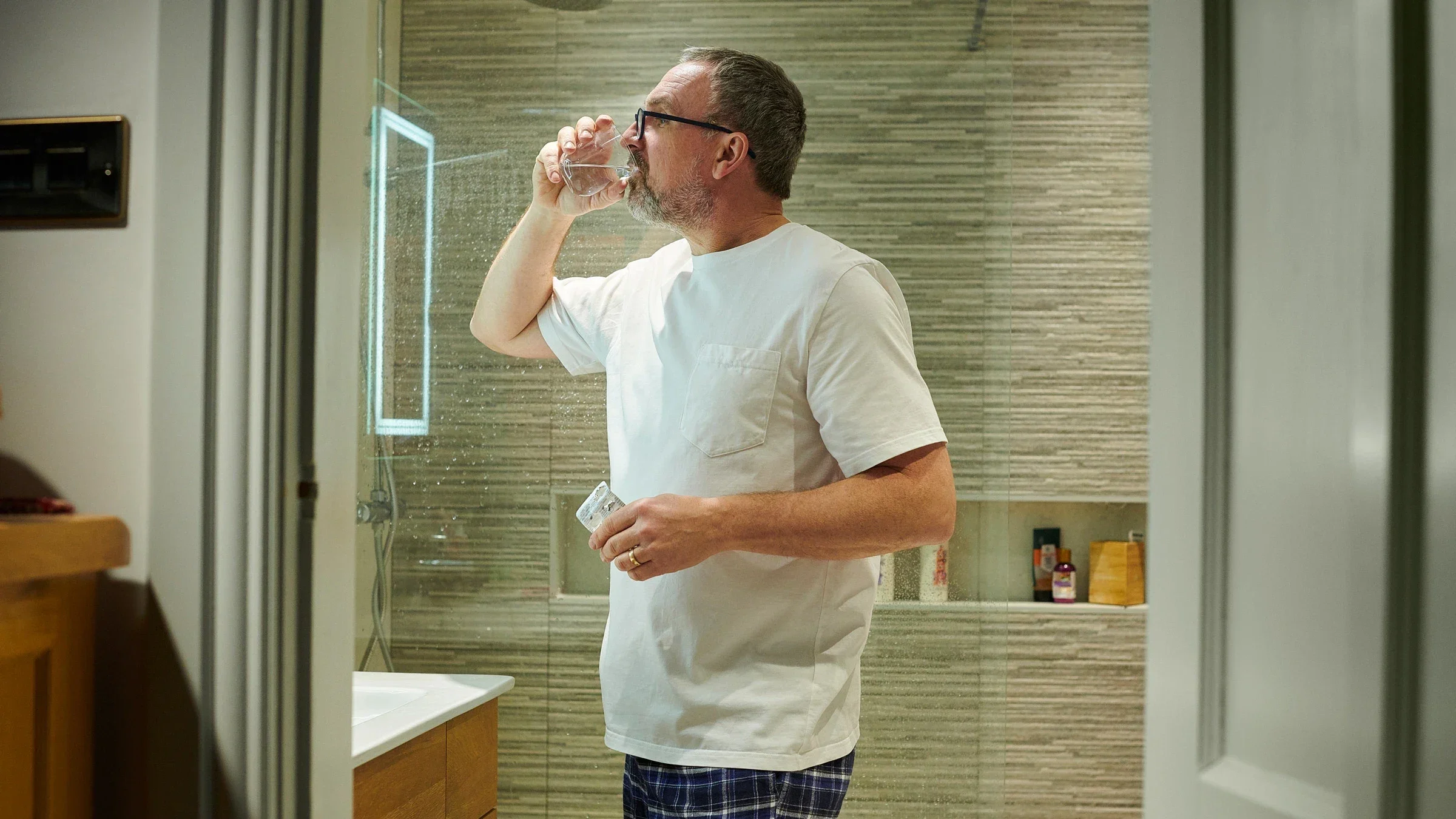 A man taking a pill in his bathroom before bedtime.
sturti/E+ via Getty Images 