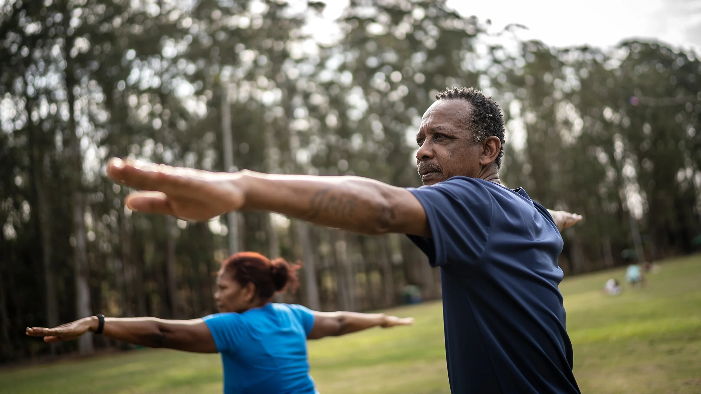 Man and woman practicing yoga in a park