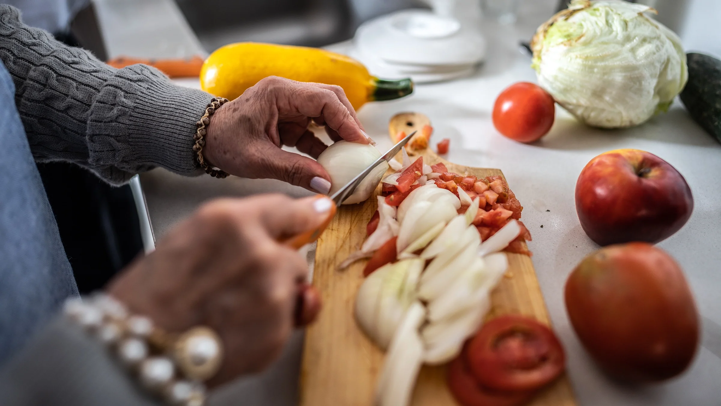 Close-up hands slicing onions.