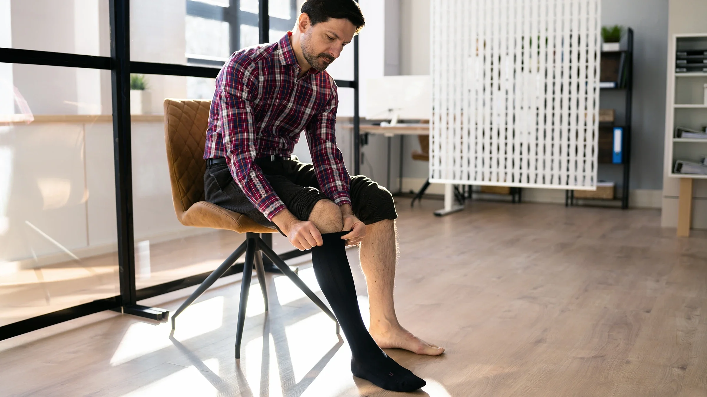 A man puts on compression socks.
