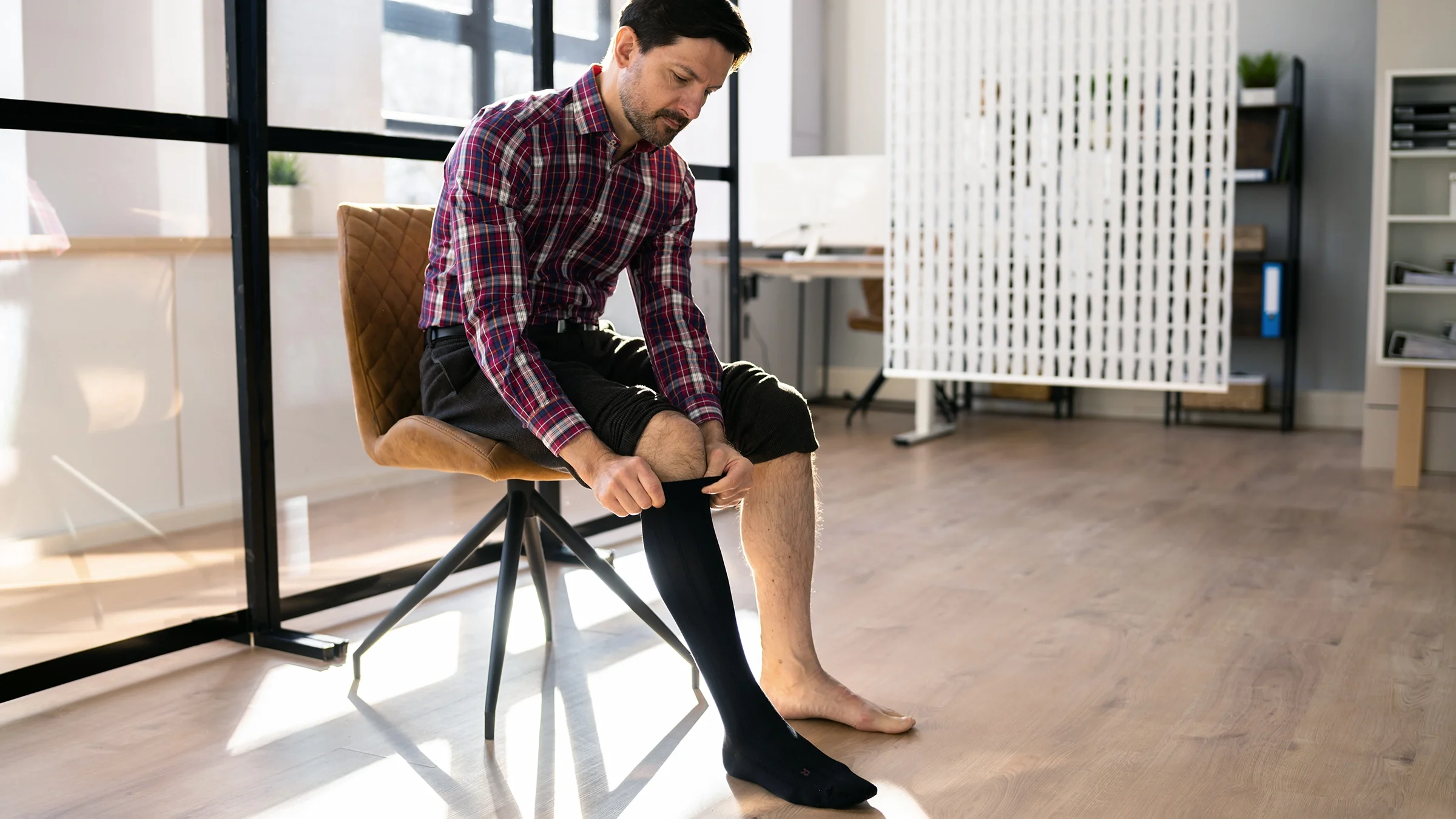 A man puts on compression socks.