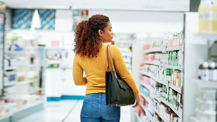 A woman browses the shelves of a pharmacy.