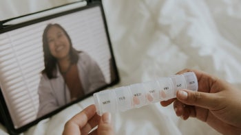 Providers: Telehealth: pill container pharmacist on tablet in background 1394231084