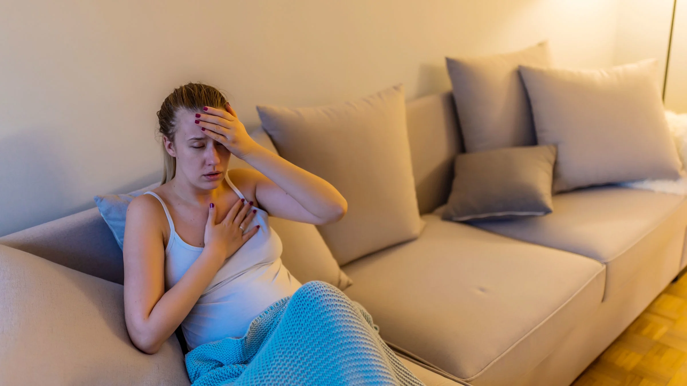 A woman is sitting on a couch with symptomatic chest pain.