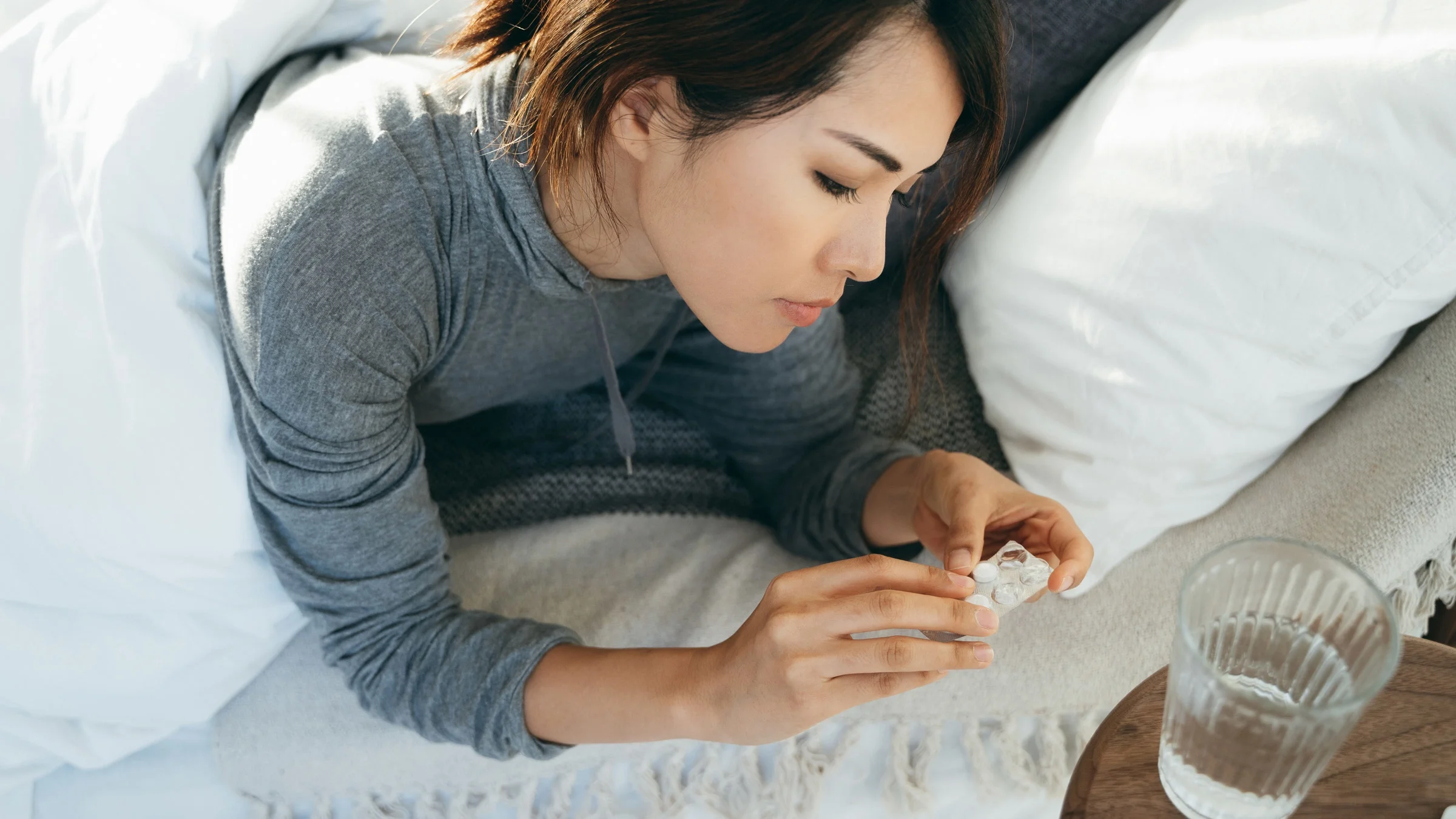 A person taking a medication in bed.