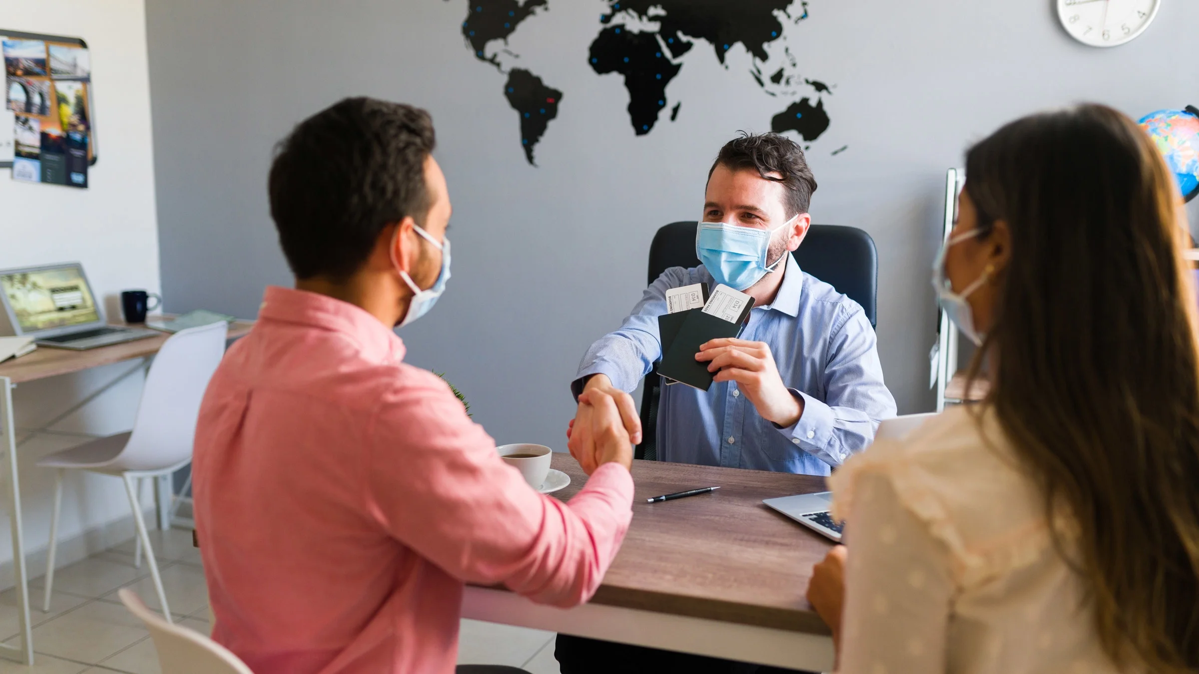 A couple talking to a travel agent. They're all masked.