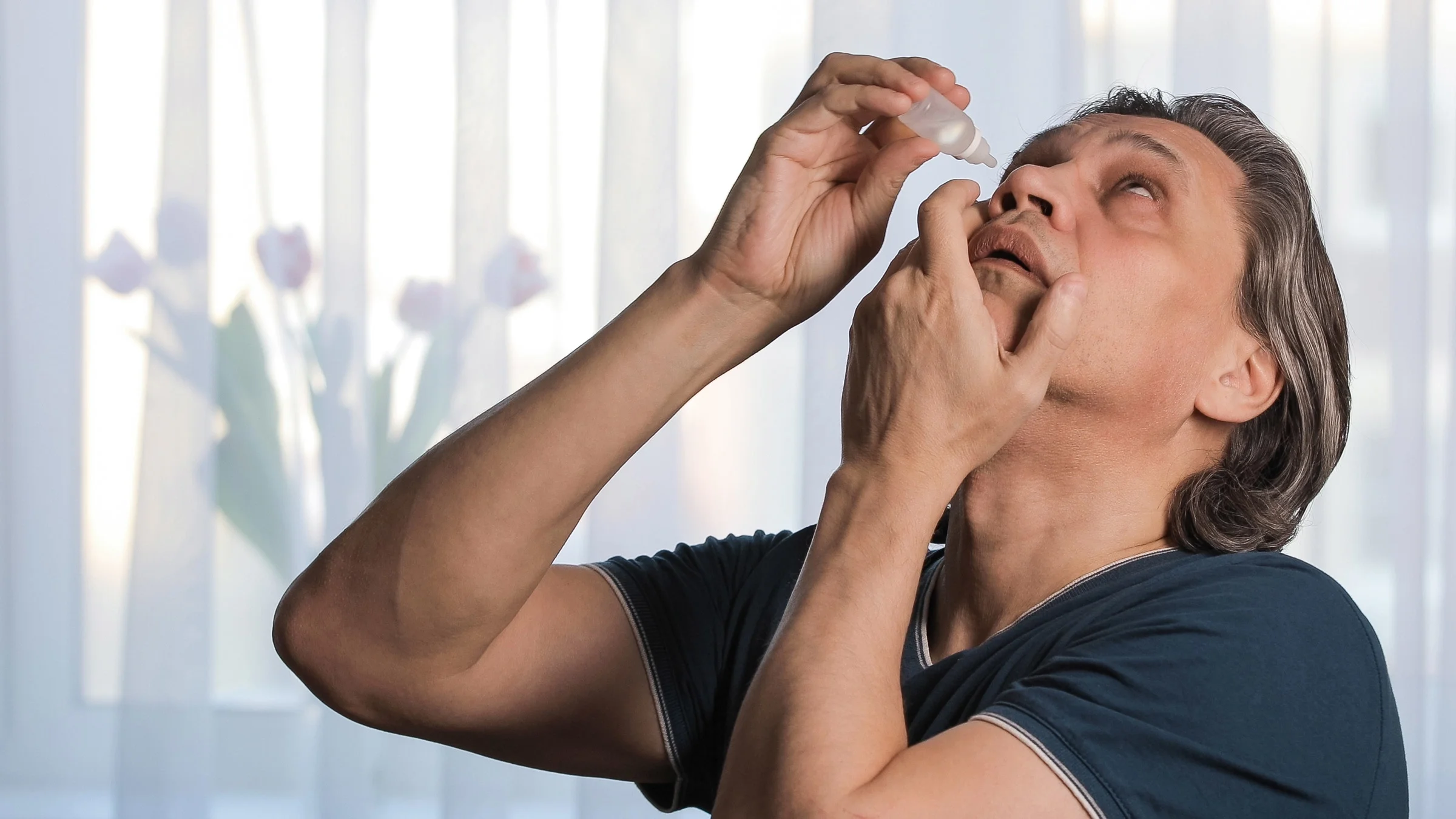 A person applying eye drops.