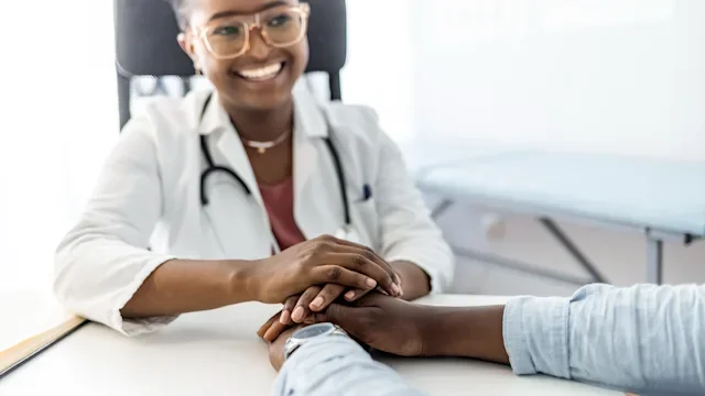 doctor smiling and holding patients hands 1325865279
