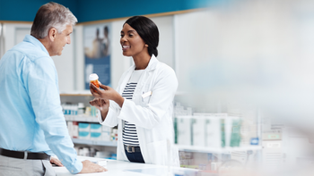 pharmacist-and-patient-at-counter-1098324584
