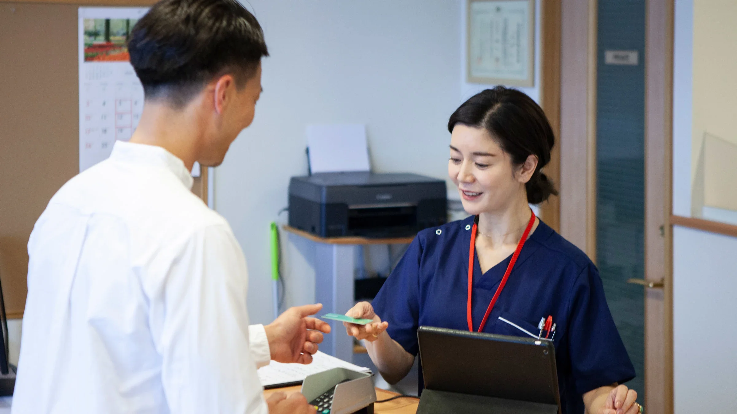 A patient paying with a credit card at a reception desk.
kokouu/E+ via Getty Images
