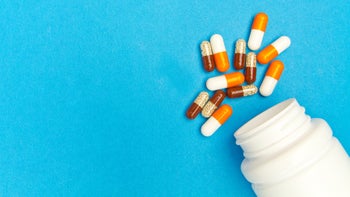 orange and white pills white pill bottle blue background-1136404287