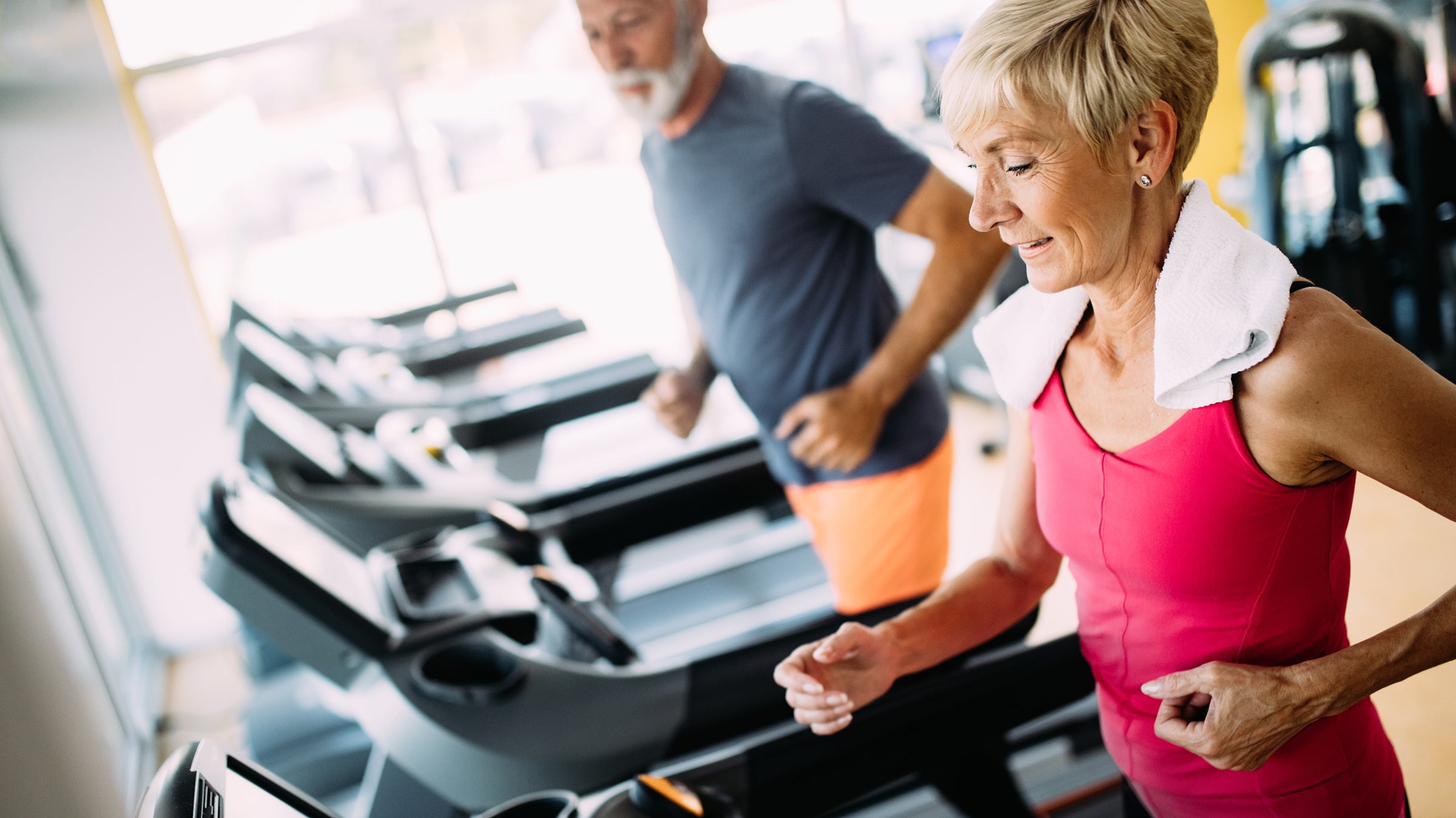 Health: Health insurance: senior couple at gym on tredmills-1171659624