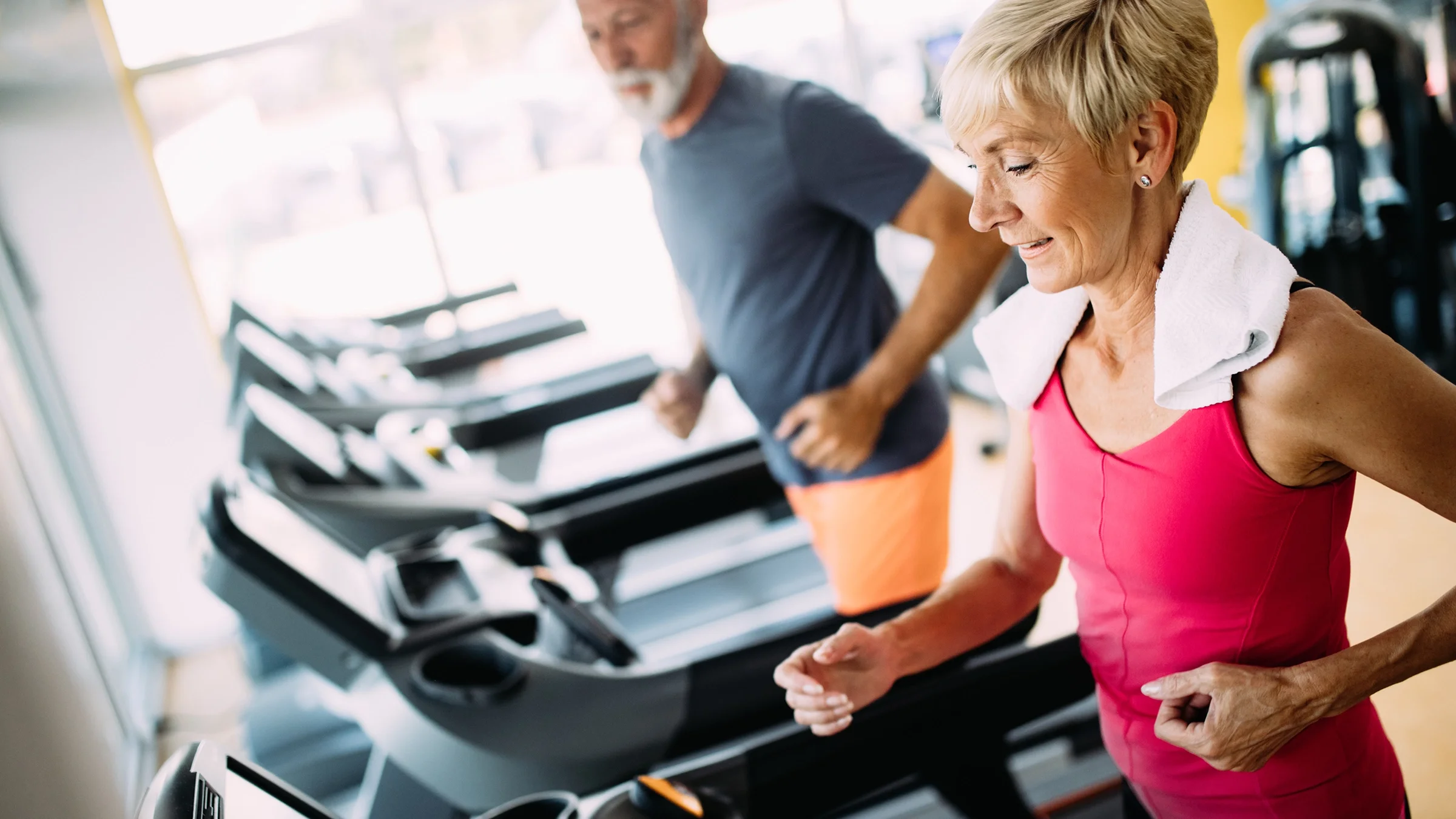 Senior couple at the gym on the treadmills.