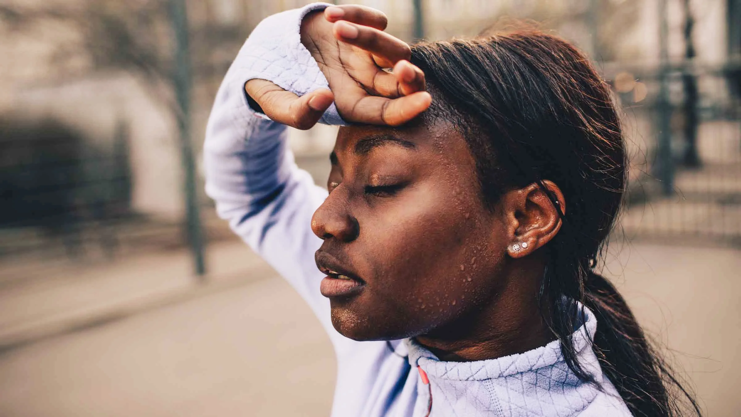 A woman wipes sweat from her forehead after a workout.
