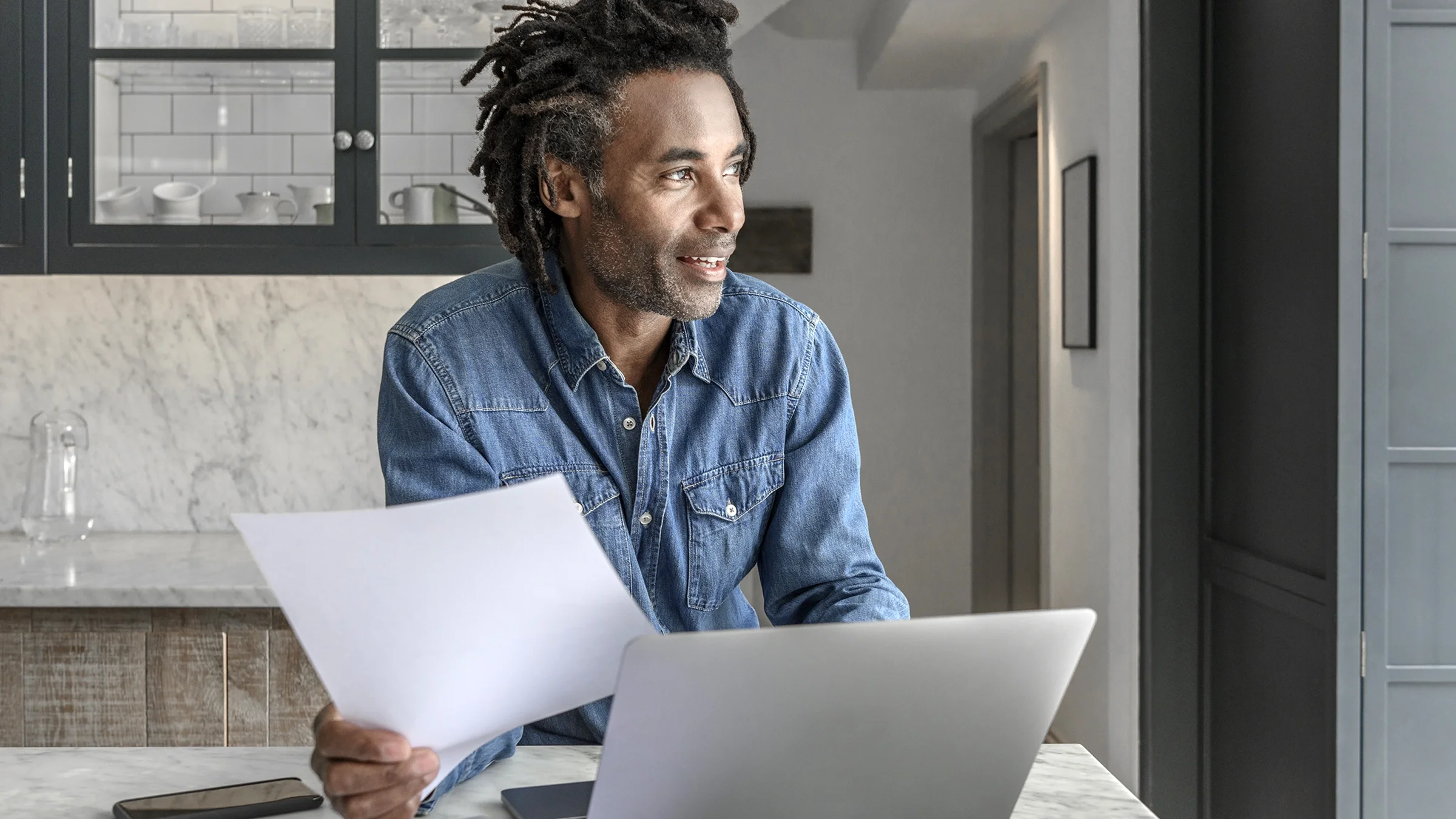 Man reviewing paperwork in his kitchen.