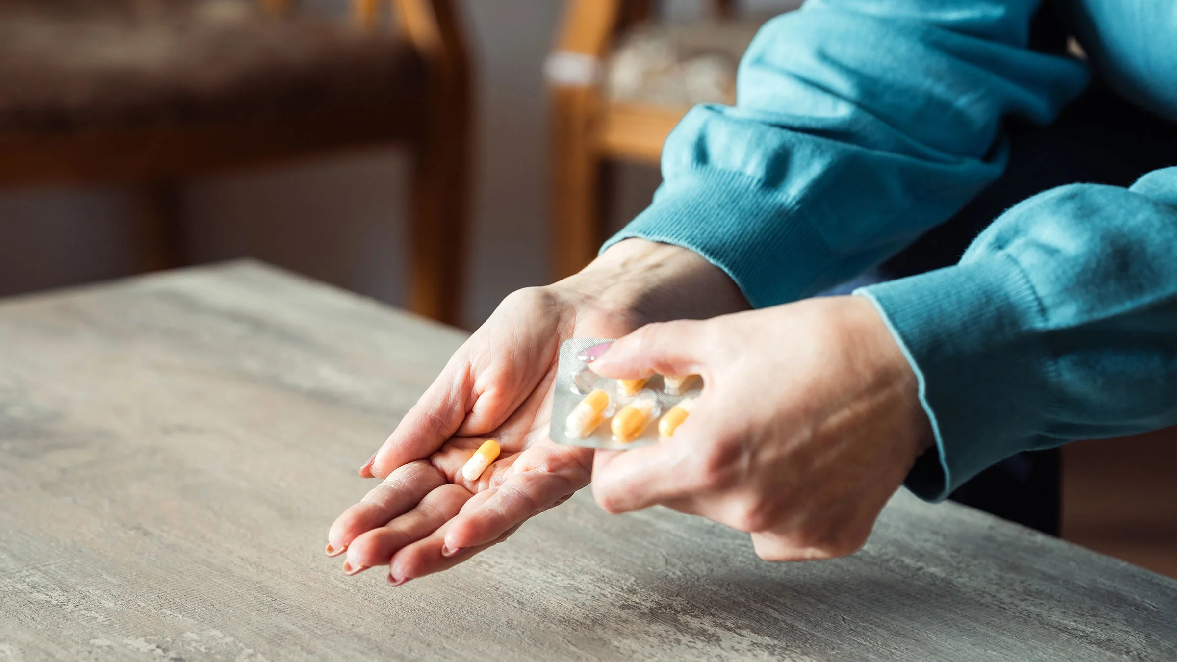 A woman takes pills from a blister pack.