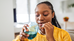 Woman sitting on a sofa and taking a pill.
stefanamer/iStock via Getty Images Plus  