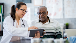 A medical professional speaks to a patient while holding a tablet
FatCamera/E+ via Getty Images
