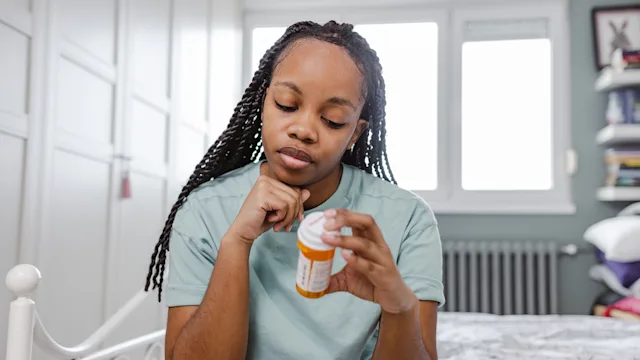 adhd: woman reading Rx bottle 1466975060