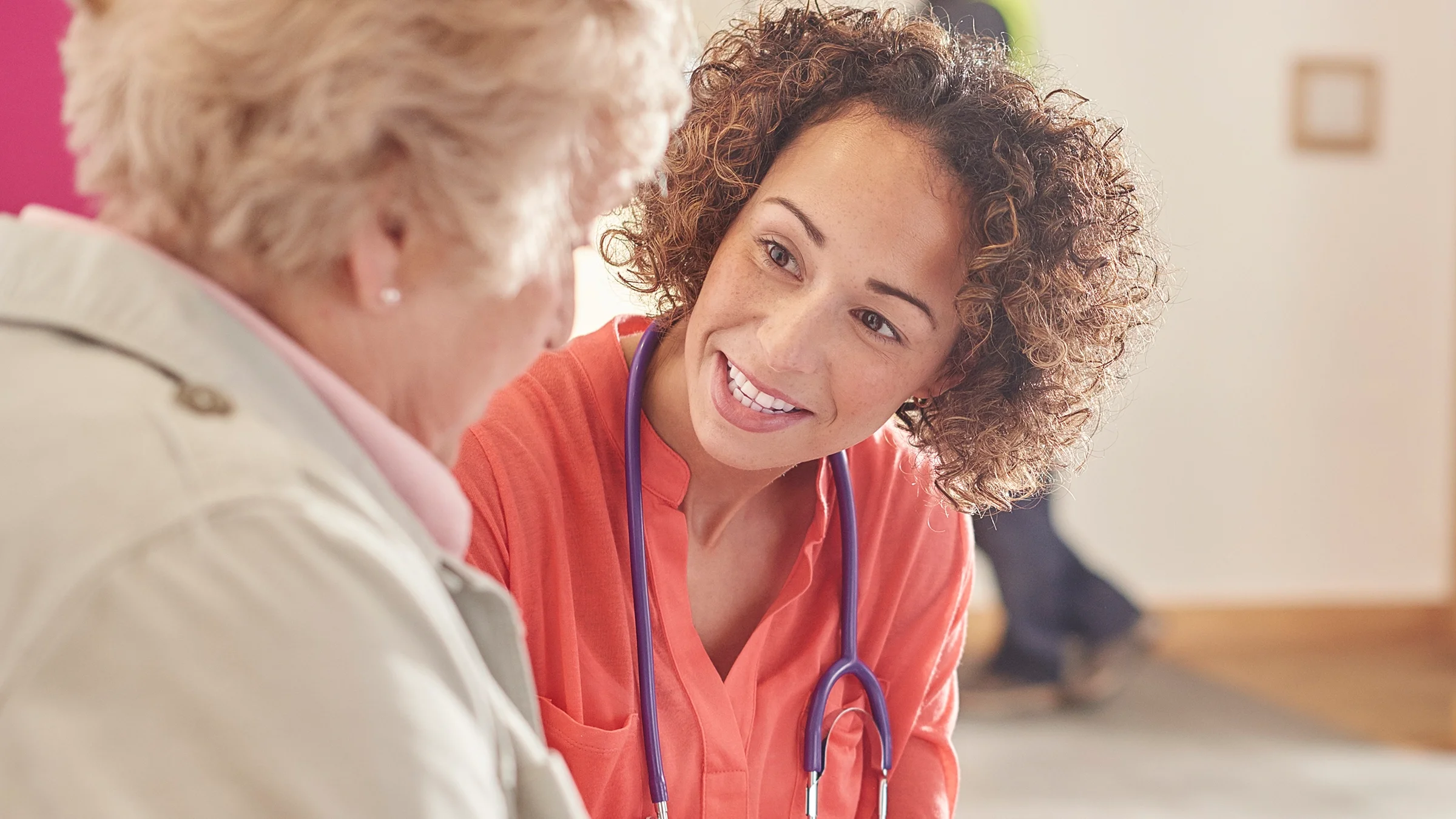 Nurse sitting down with patient and leaning in with a kind expression.