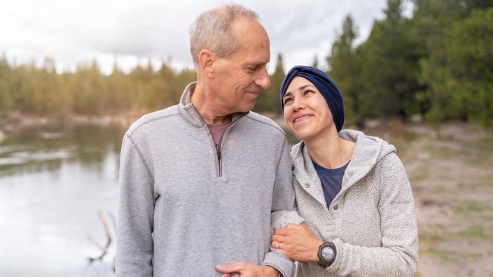 A cancer patient hugging dad's arm while walking in nature.