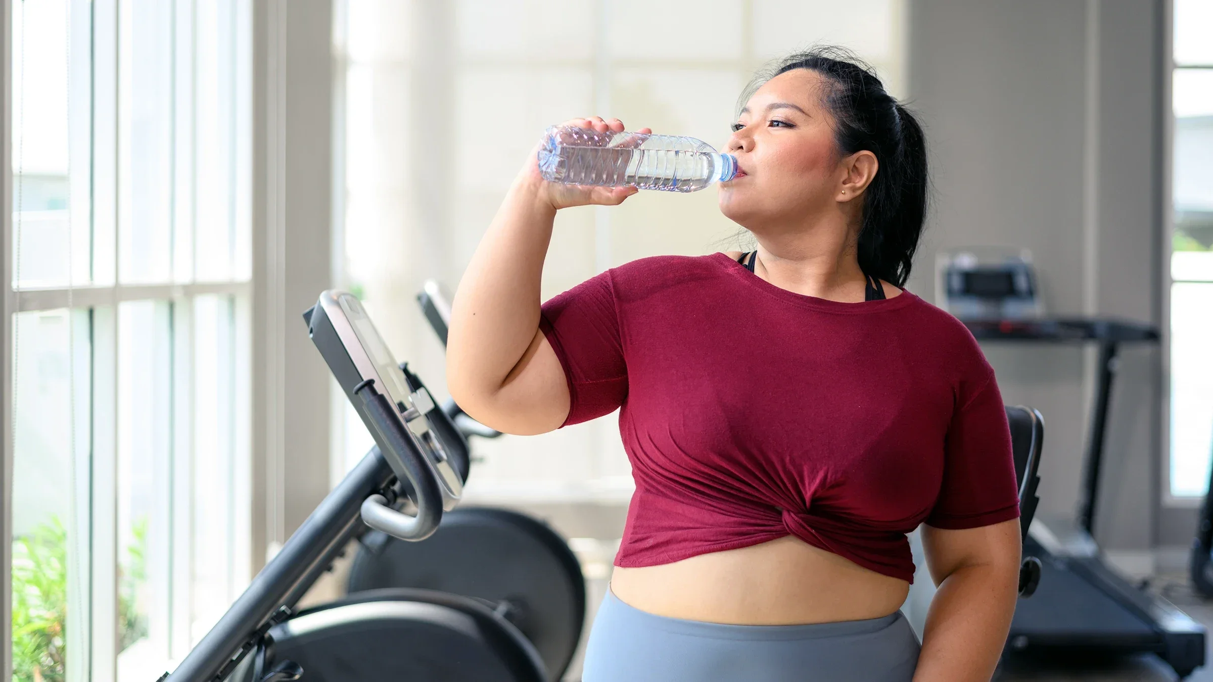 A woman drinks water from a bottle after a workout session at the gym. 
Pratchaya/iStock via Getty Images Plus