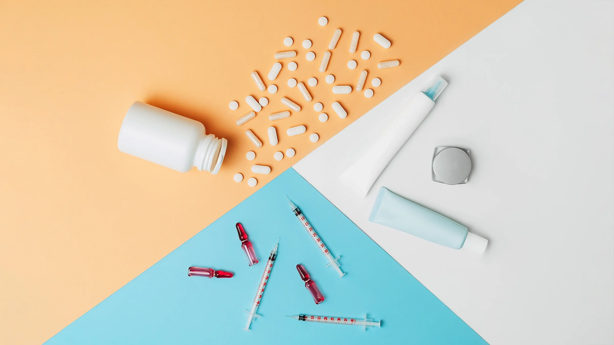 Spilled pill bottle, syringes, and lotion bottles on a geometric pastel colored background.