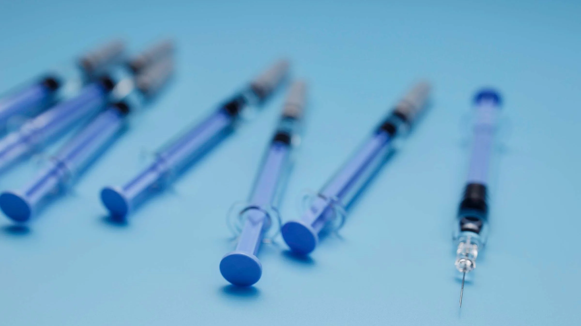 Blue syringes on a light blue background.