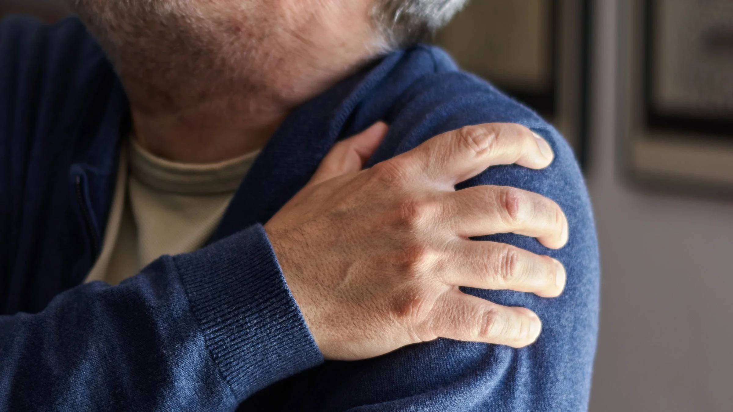 A man is grabbing his shoulder from pain.