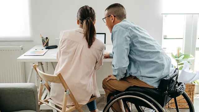 Taxes: disability income: wheelchair user partner looking at laptop 1323386472