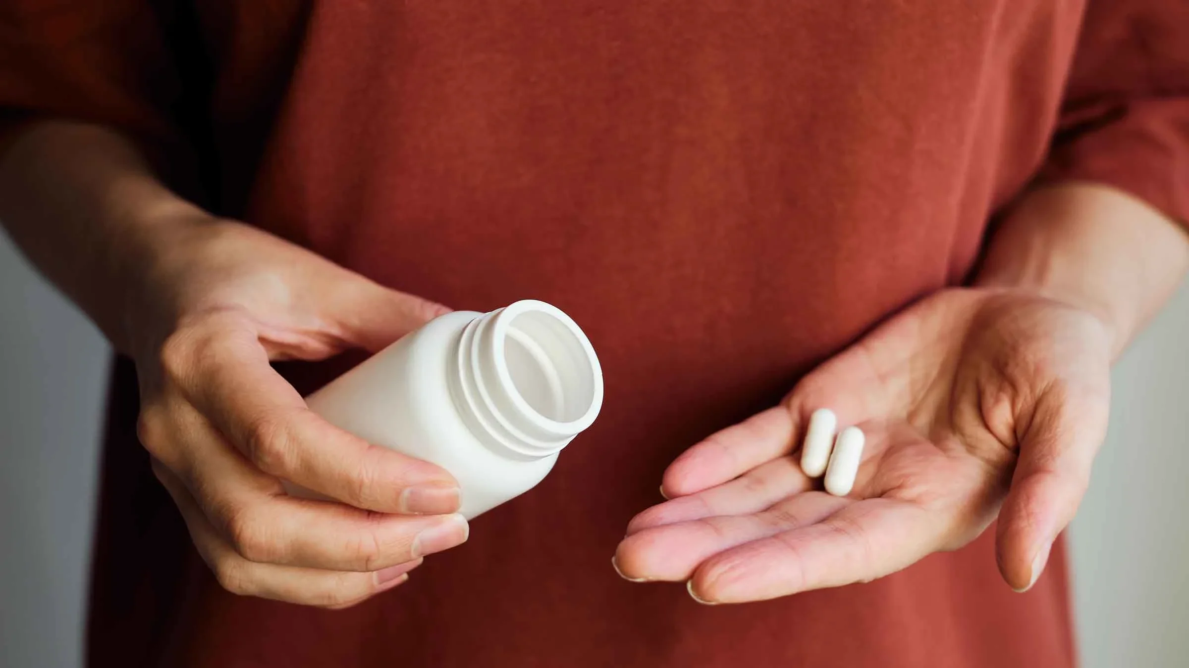 A woman pours pills from a jar onto her hand.
Iuliia Pilipeichenko/iStock via Getty Images Plus