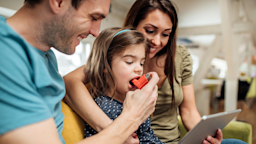 Parents help their daughter use an asthma inhaler.
RgStudio/E+ via Getty Images