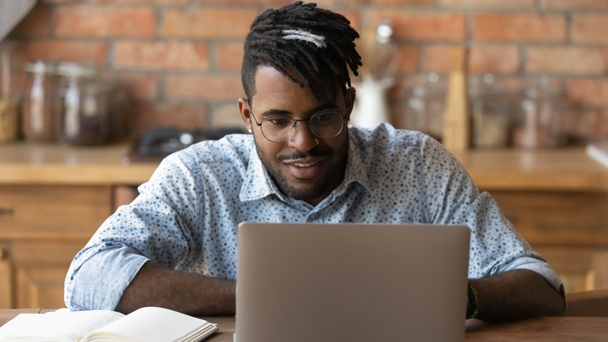 Young man looking up something on his laptop at a coffee shop table.
