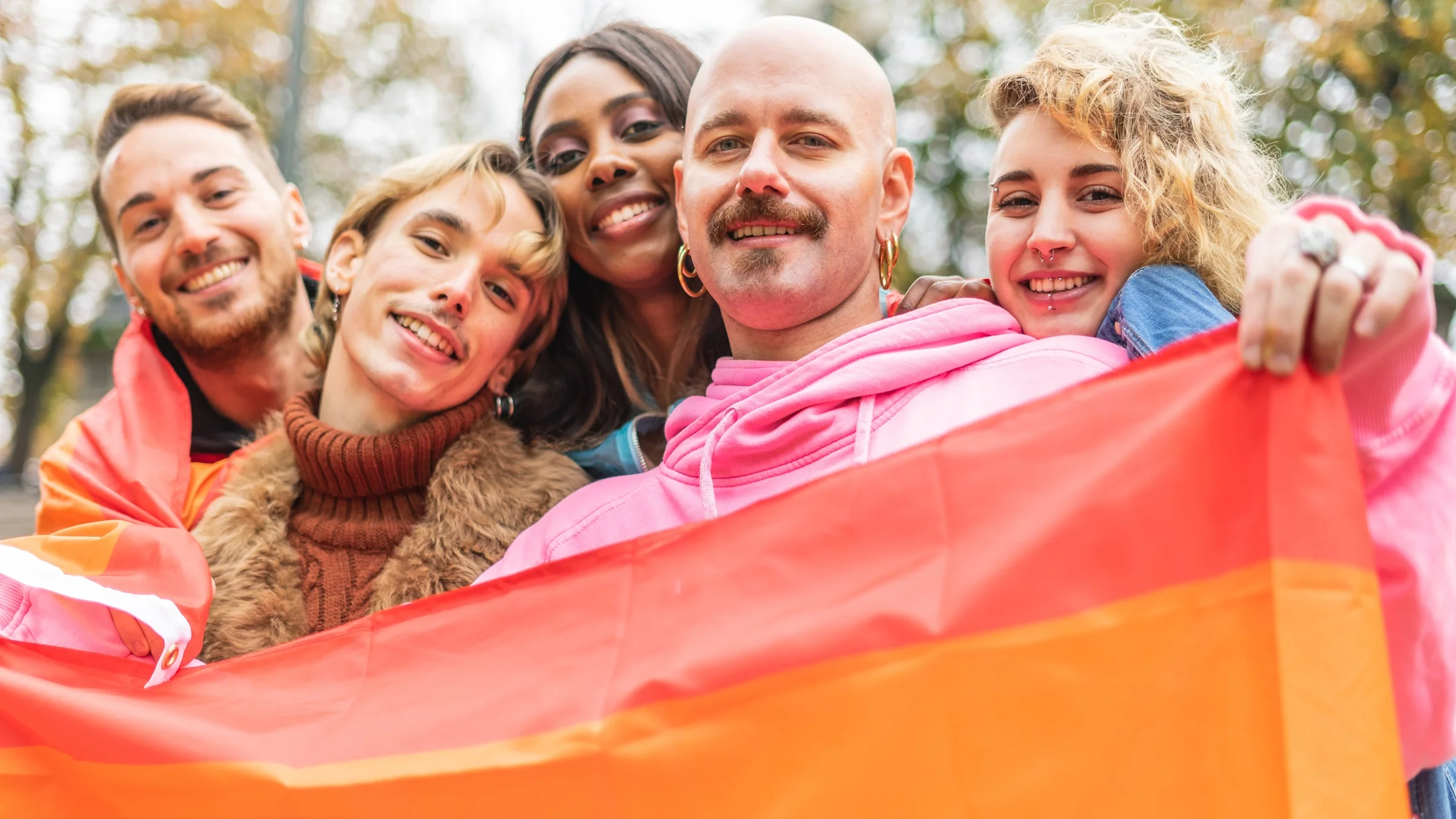 A group of friends holding a pride flag.
