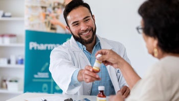 savings: pharmarcist assists customer 1165345981
