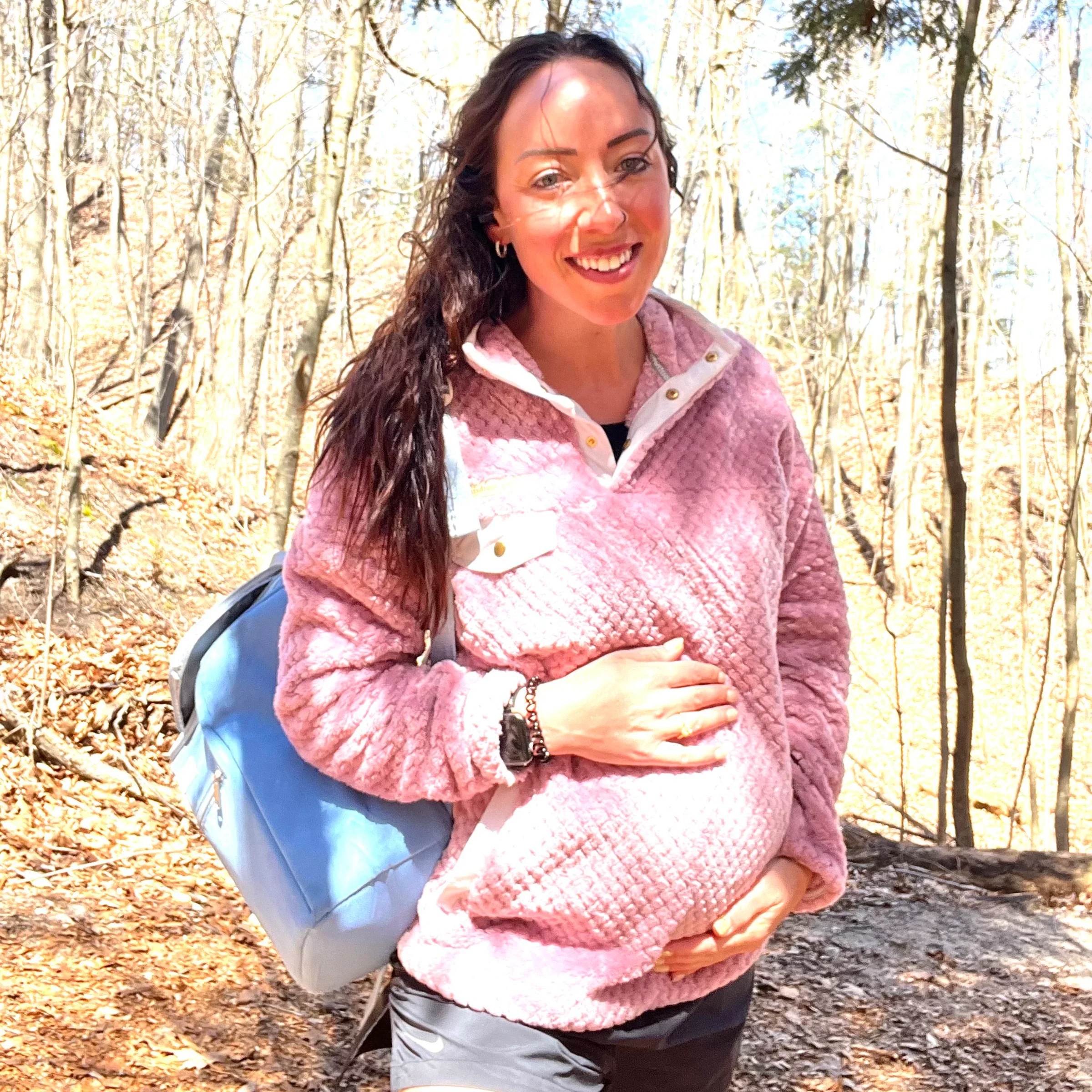 Deb Oliviara is pictured on a hike, with her hands on her pregnant belly.